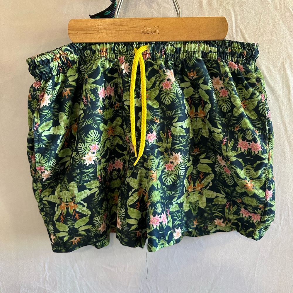 Men’s swimming trunks. Green tropical pattern.